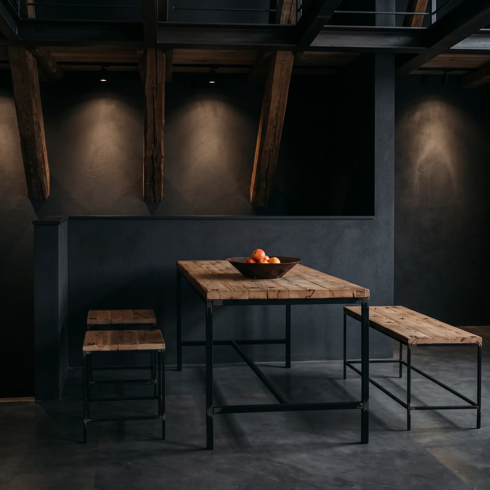 Esstisch und Bänke aus Altholz mit schwarzem Metallgestell in einem dunklen Industrial-Loft